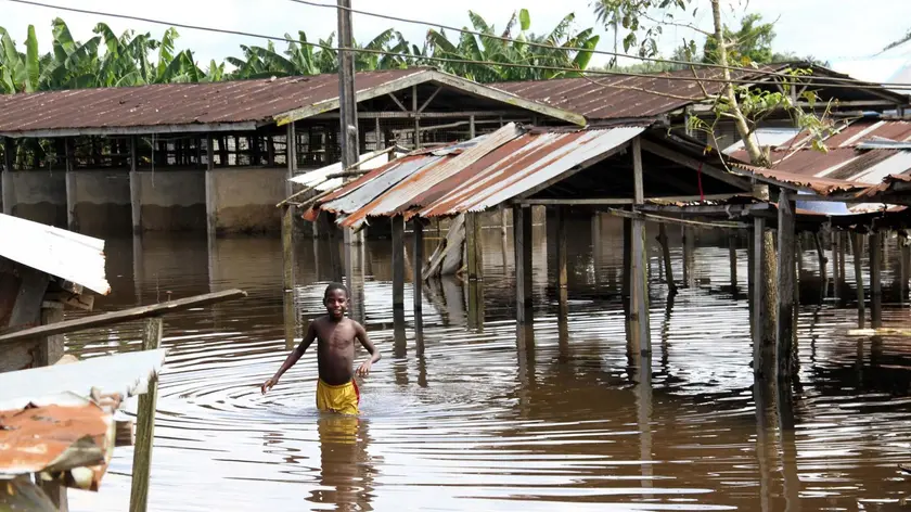 epa03432194 A boy wades through a flooded market in Agadama in Ughelli north local government council in the oil rich Niger delta region, Nigeria, 13 October 2012. The floods in the region, which have been the worst in decades, have killed 140 people and left hundreds of thousands homeless. A food crisis is also feared, according to local sources. EPA/GEORGE ESIRII