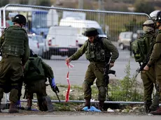 epa05037279 Israeli soldiers pick up debris and bloodied pieces of their investigation at the scene of a Palestinian attack on a bus stop and hitch hiking post outside Efrat in the West Bank settlement block of Gush Etzion, south of Jerusalem, 22 November 2015. A female Israel died from her stabbing wounds inflicted by a Palestinian woman who attacked with a knife. The atacker was shot dead at the scene by Israeli security forces. EPA/JIM HOLLANDER