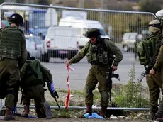 epa05037279 Israeli soldiers pick up debris and bloodied pieces of their investigation at the scene of a Palestinian attack on a bus stop and hitch hiking post outside Efrat in the West Bank settlement block of Gush Etzion, south of Jerusalem, 22 November 2015. A female Israel died from her stabbing wounds inflicted by a Palestinian woman who attacked with a knife. The atacker was shot dead at the scene by Israeli security forces. EPA/JIM HOLLANDER