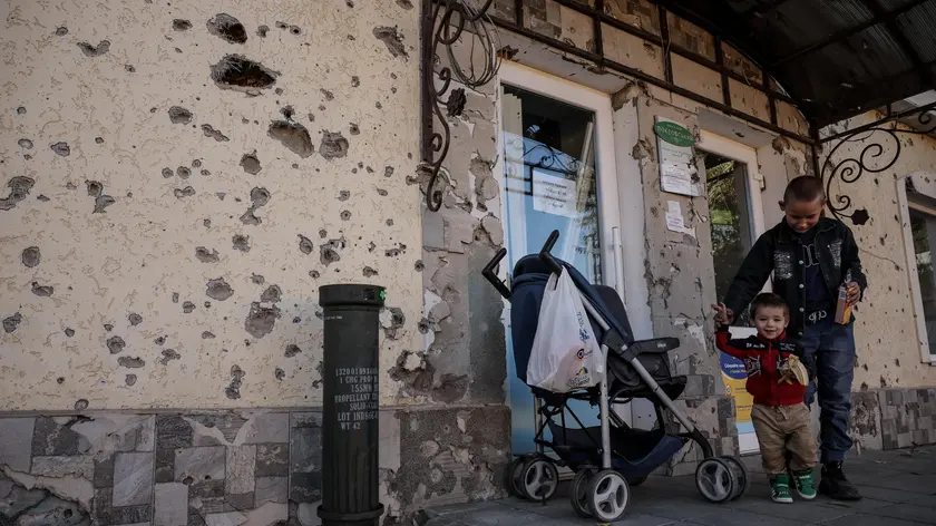 epa10954197 Nine-year-old Maksym and his one-year-old cousin Mykyta outside a grocery store in the village of Posad-Pokrovske in the Kherson region, 01 November 2023. Russia bombarded 118 Ukrainian towns and villages in 24 hours, more than on any other day this year, Ukrainian Interior Minister Ihor Klymenko announced 02 November 2023. Russian troops entered Ukrainian territory in February 2022, starting a conflict that has provoked destruction and a humanitarian crisis. EPA/Oleg Petrasyuk