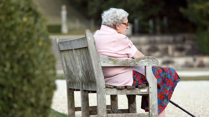Senior woman sitting on a bench in a public garden