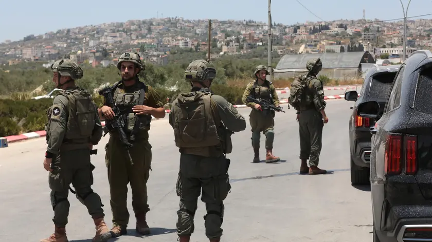 epa10690629 Israeli soldiers stop Palestinians as they try to leave the Palestinian village of Yabad near the West Bank city of Jenin, 14 June 2023. The Israeli army closed access to the village after an Israeli motorist and four Israel soldiers were wounded during a shooting near the northern West Bank settlement of Mevo Dotan on 13 June afternoon. The shooters had opened fire from their car at an Israeli vehicle, then also shot a military vehicle with Israeli soldiers inside, who were stationed at a military post near Ya'bad. EPA/ALAA BADARNEH