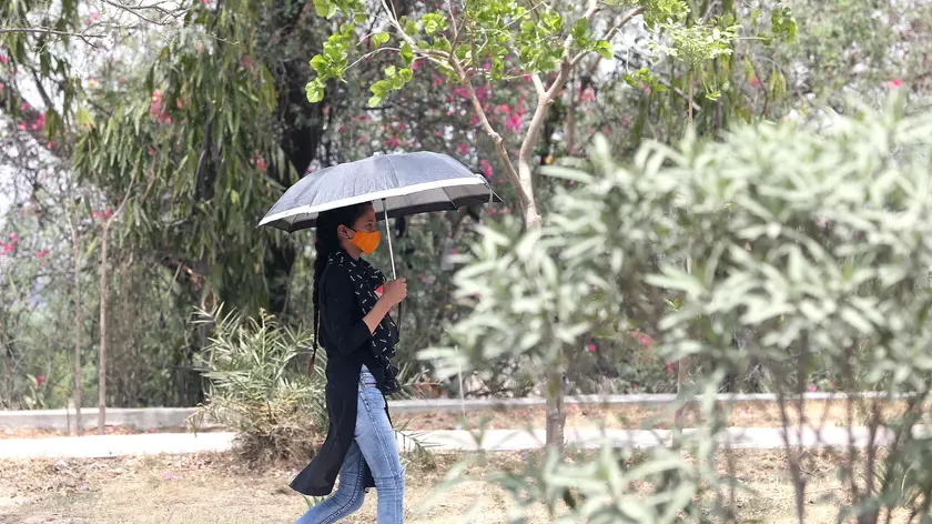 epa09957281 A woman walks with her umbrella to avoid the heatwave during a hot afternoon on the outskirts of New Delhi, India, 19 May 2022. According to the India Meteorological Department (IMD), Delhi and National Capital Region's temperature is expected to exceed 43 degrees Celsius amid a heat wave which is continuing with its fresh spell. EPA/HARISH TYAGI