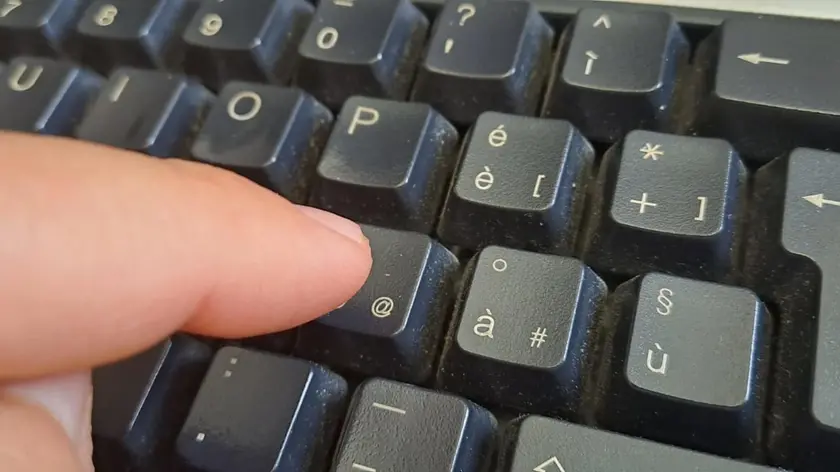 Dettaglio dell'indice di un uomo che sta pigiando il tasto della chiocciolina sulla tastiera del suo pc, Cagliari, 21 novembre 2023. ANSA / FABRIZIO FOIS (tastiera, dito, generica)
