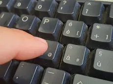Dettaglio dell'indice di un uomo che sta pigiando il tasto della chiocciolina sulla tastiera del suo pc, Cagliari, 21 novembre 2023. ANSA / FABRIZIO FOIS (tastiera, dito, generica)