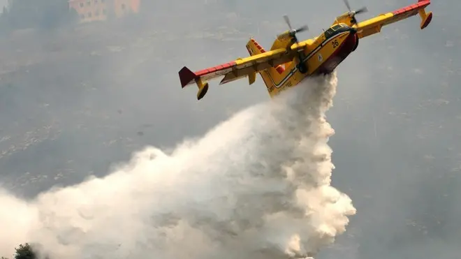 20090907 - GENOVA - DIS - INCENDI: GENOVA ANCORA ASSEDIATA, CENERE SULLA CITTA' - Incendi nel Levante genovese, canadair in azione all'altezza del casello di Genova Nervi oggi 7 agosto 2009. Gli eleganti quartieri residenziali del Levante genovese, Quarto, Quinto e Nervi, si sono svegliati stamani sotto una leggera "nevicata" di cenere che ha coperto terrazzi, balconi ed automobili. Il cielo è velato dal fumo del grande incendio che da ieri pomeriggio assedia la città dalle pendici del Monte Moro. Dall'alba si sono levati in volo i canadair e gli elicotteri della Protezione civile, che continuano a fare la spola tra il mare e le vicine pinete in collina avvolte da nubi di fumo. Spettacolari i passaggi dei velicoli radenti i tetti. ANSA/LUCA ZENNARO/GID