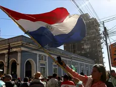 epa06111083 A demonstrator flies a Paraguayan flag during a farmers march, in Asuncion, Paraguay, 26 July 2017. Riot Police of the National Police prevented the advance of thousands of protesters to the Lopez Palace, the seat of the Government. Farmers have been protesting for more than three weeks demanding the government follow through on a promise to refinance debts. EPA/Andres Cristaldo