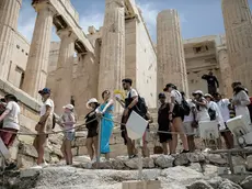 epa11403675 A visitor uses a handheld fan as tourists line up to exit the Acropolis during a heatwave, in Athens, Greece, 11 June 2024. The extended high pressure area over the coasts of Africa and central Mediterranean, which is accompanied by very warm air masses, is gradually extending eastward and will bring very high temperatures in Greece from 11 until 14 June. A circular of the Interior Ministry outlines how civil services will operate during the heatwave forecast in Greece by the National Meteorological Service. EPA/KOSTAS TSIRONIS