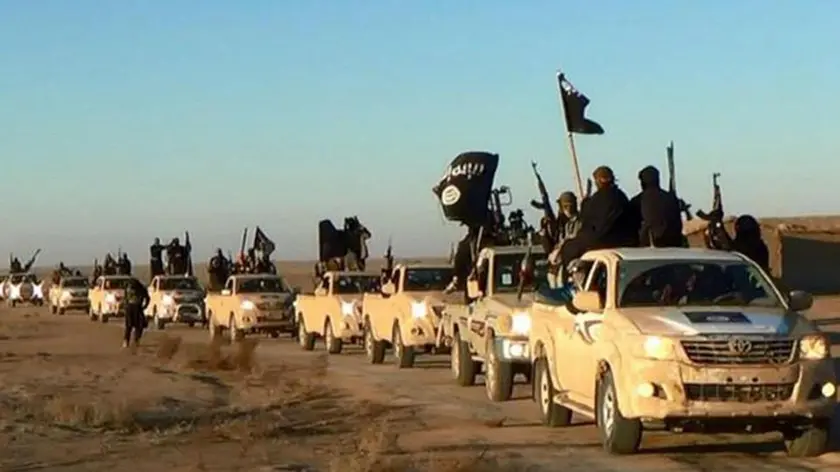 FILE - In this undated file photo released by a militant website, which has been verified and is consistent with other AP reporting, militants of the Islamic State group hold up their weapons and wave its flags on their vehicles in a convoy on a road leading to Iraq, while riding in Raqqa city in Syria. (Militant website via AP, file)