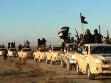 FILE - In this undated file photo released by a militant website, which has been verified and is consistent with other AP reporting, militants of the Islamic State group hold up their weapons and wave its flags on their vehicles in a convoy on a road leading to Iraq, while riding in Raqqa city in Syria. (Militant website via AP, file)