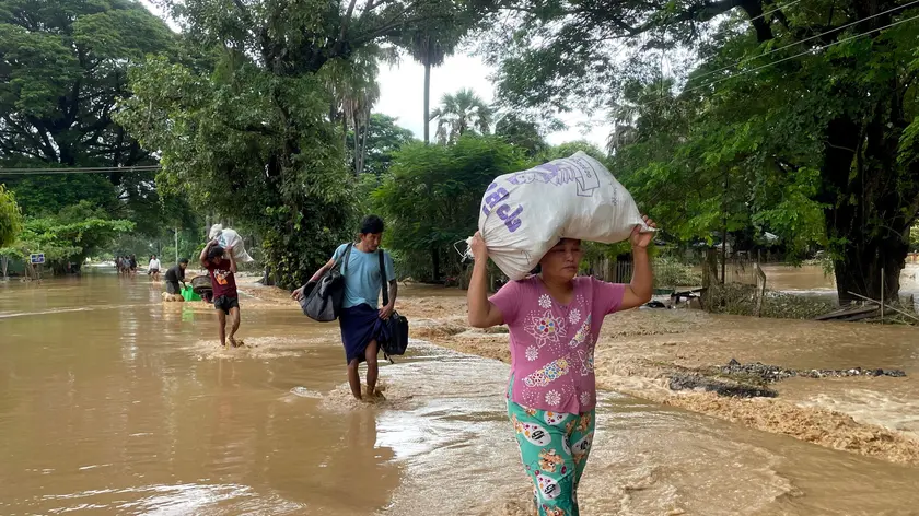 epa11601503 People carry their belonging as they wade through flood waters in Pyinmana, Naypyidaw, Myanmar, 13 September 2024. Heavy rains triggered by Typhoon Yagi have caused severe flooding in parts of Myanmar, leaving thousands stranded in their homes, with further heavy rainfall and thunderstorms expected, according to the state weather office. EPA/NYEIN CHAN NAING