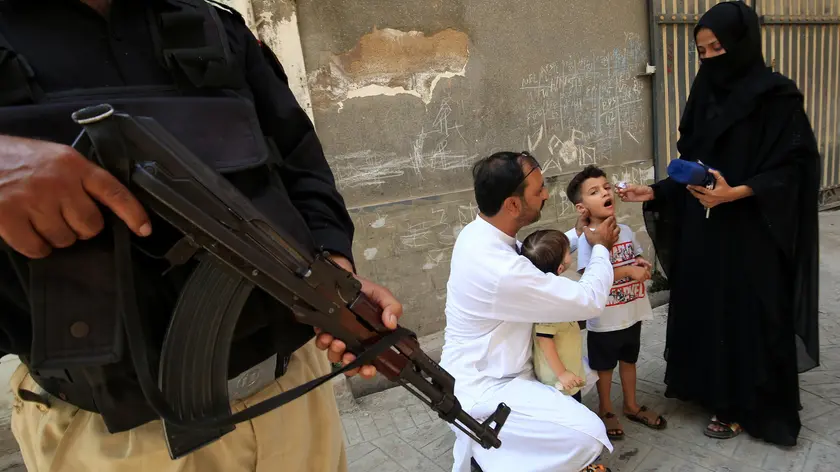 epa11599890 A police officer stands guard as a health worker administers polio vaccine drops to a child during a door-to-door vaccination campaign in Peshawar, Pakistan, 12 September 2024. A polio vaccination worker and a police officer providing security were killed during a polio vaccination campaign near the Afghan border in Bajaur district, Khyber Pakhtunkhwa, on 11 September 2024, after an attack by suspected militants. The police cordoned off the area and initiated a search operation for the attackers, while the bodies were taken to Khar Hospital. This incident highlights the ongoing violence aimed at disrupting polio eradication efforts in the region, despite existing security measures. Pakistan is one of the last two countries, along with Afghanistan, where the polio is still endemic, meaning infections occur within the local population or within a particular area. EPA/ARSHAD ARBAB