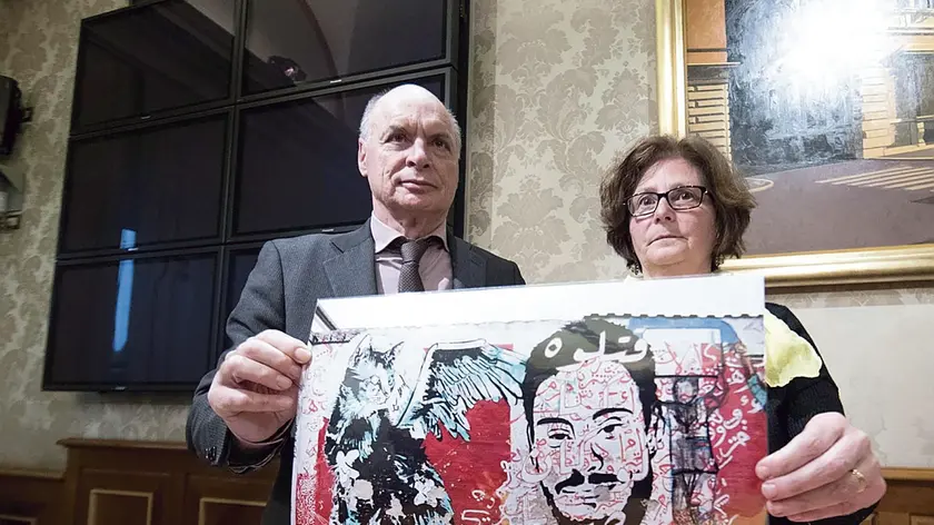 Parents of Giulio Regeni, Claudio (L) and Paola, show the picture of a mural made upon a wall in Berlin, by Egyptians writers, with the image of their son and a stylized cat during a press conference at the Italian Senate, 04 April 2017. Regeni's parents appealed to Pope Francis to bring up the case of the Italian student tortured and murdered in Cairo when he visits Egypt on April 28-29. ANSA/MASSIMO PERCOSSI