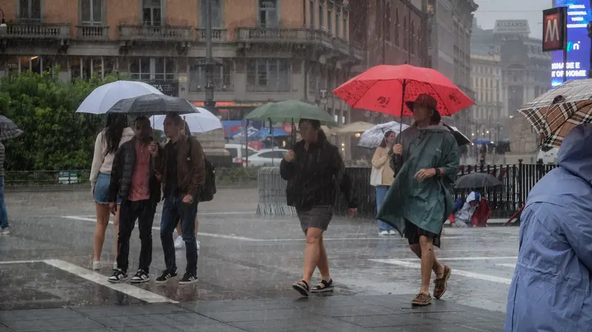 Persone si riparano dalla pioggia con un ombrello durante un temporale a Milano, 5 settembre 2024. ANSA/MATTEO CORNER