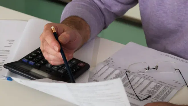 Mature man sitting at desk checking bills, close-up
