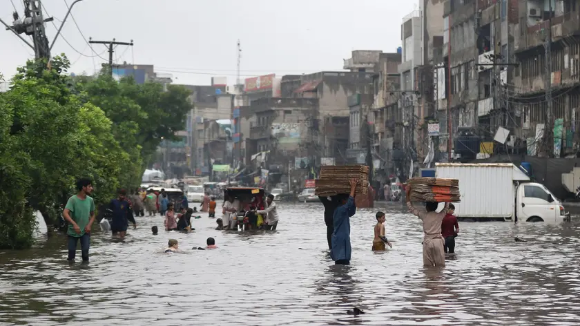 epa11515513 People and vehicles make their way through a water-logged street after heavy rainfall in Lahore, Pakistan, 01 August 2024. Lahore experienced heavy monsoon rains on Thursday, with 350 millimetres recorded in just three hours, shattering a 44-year-old rainfall record, MET office said. The downpour caused significant flooding in various areas, including Mall Road, Ferozepur Road, and Model Town, while rainwater inundated homes in Tajpura and disrupted operations at Services Hospital. The Lahore Electric Supply Company reported widespread power outages due to 288 tripped feeders, urging consumers to be patient as restoration efforts were underway. The Pakistan Meteorological Department warned of more torrential rains expected across the upper regions of the country from August 01 to 06. EPA/RAHAT DAR