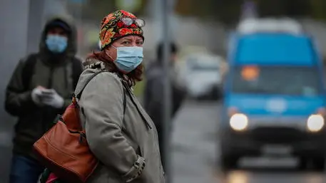 epa08750280 Russian people wearing a protective face masks waiting a bus on the bus stop in Moscow, Russia, 15 October 2020. According to official information, in the past 24 hours Russia registered 15150 included 5049 in Moscow new cases caused by the SARS-CoV-2 coronavirus infection. EPA/YURI KOCHETKOV