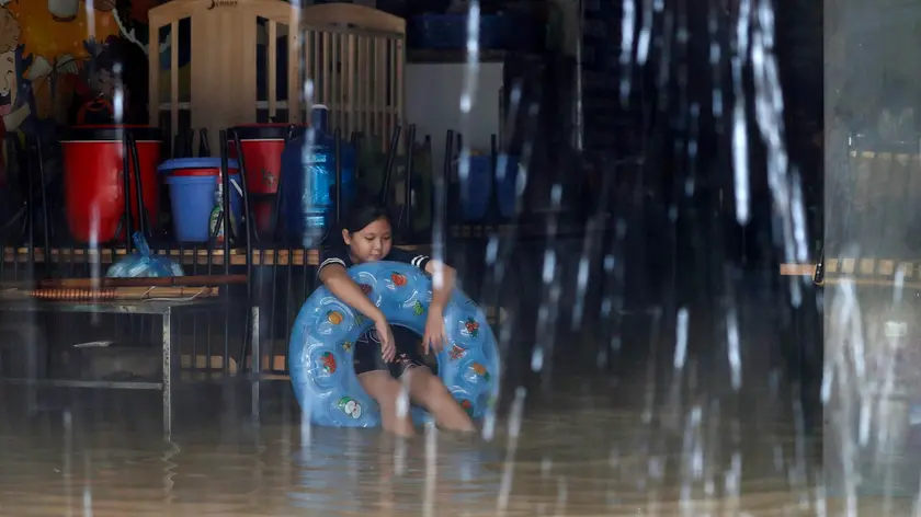 epa11597963 A girl sits inside her flooded home in Hanoi, Vietnam, 11 September 2024. Typhoon Yagi, which struck northern Vietnam over the weekend, triggered severe flooding in Hanoi. The Red River's rapid rise inundated communities along the riverbank, forcing residents to seek refuge in safer areas. As of 11 September, the Vietnam Disaster and Dyke Management Authority reported at least 152 fatalities and 140 missing persons due to the typhoon. EPA/LUONG THAI LINH