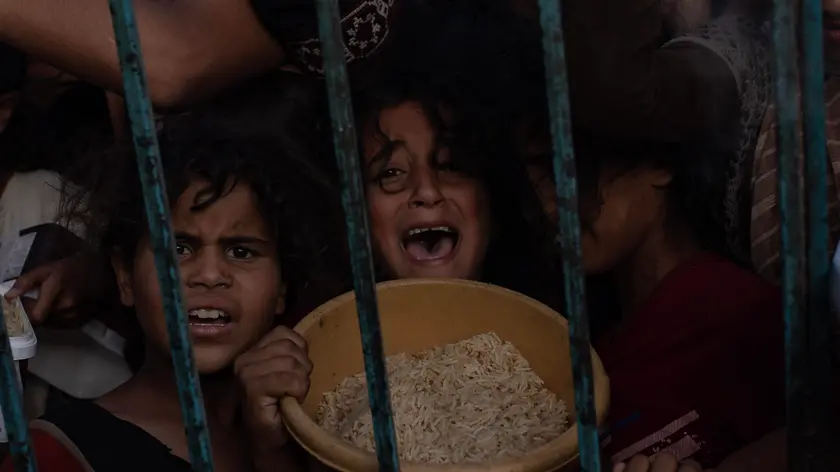 epa11413739 Children stand at a gathering of internally displaced Palestinians to collect food donated by a charitable group, in Khan Yunis camp, southern Gaza Strip, 15 June 2024. Since 07 October 2023, up to 1.7 million people, or more than 75 percent of the population, have been displaced throughout the Gaza Strip, some more than once, in search of safety, according to the United Nations Relief and Works Agency for Palestine Refugees in the Near East (UNRWA), which added that the Palestinian enclave is 'on the brink of famine', with 1.1 million people (half of its population) 'experiencing catastrophic food insecurity' due to the conflict and restrictions on humanitarian access. EPA/HAITHAM IMAD
