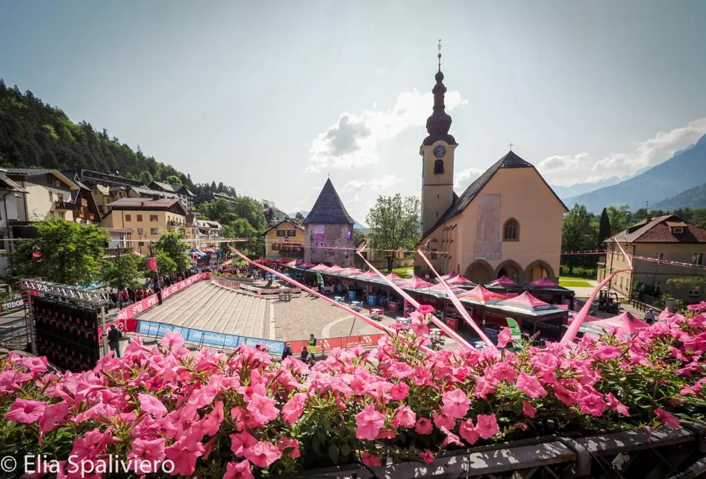 Splende il sole, intanto, in Friuli. Finalmente bel tempo sul Giro inseguito per giorni e giorni dalla pioggia nella sua risalita al Nord; spettacolo fino all’ultimo per una classifica apertissima come non mai. Tantissime le persone sulle strade, a Tarvisio e al Santuario, che applaudono i ciclisti ma soprattutto i due atleti friulani in gara, Alessandro De Marchi e Jonathan Milan, con la sua maglia ciclamino semplicemente passato in 21 tappe da esordiente a eroe acclamato da tutti e protagonista ieri dell’impresa del Giro arrivando in tempo massimo dopo una notte insonne. E poi turisti-tifosi in arrivo da Austria, soprattutto Slovenia per il loro Roglic; telespettatori incollati alle tv da tutto il mondo per assistere al debutto della misteriosa salita del Lussari, musica per le orecchie della Regione (Foto Petrussi)