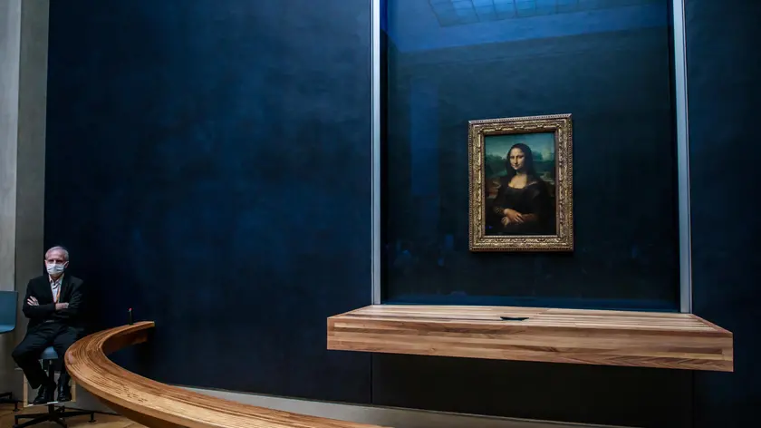 epa08530313 A guard wearing a protective face mask sits near Leonardo da Vinci's painting La Gioconda (Mona Lisa), at the Louvre Museum in Paris, France, 06 July 2020. After a nearly four-months closure due to the coronavirus pandemic, the Louvre Museum reopens to public. EPA/CHRISTOPHE PETIT TESSON